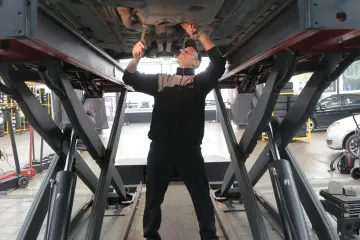 Katsastaja tarkistaa auton pohjan nosturilla Alppilan Katsastuksessa Oulussa