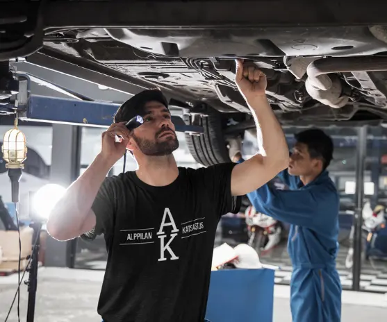 Katsastaja tarkastaa auton pohjaa taskulampulla – Alppilan Katsastus Oulussa