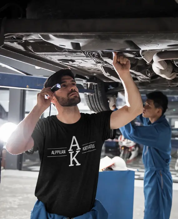 Katsastaja tutkii auton pohjaa taskulampulla jälkitarkastuksessa