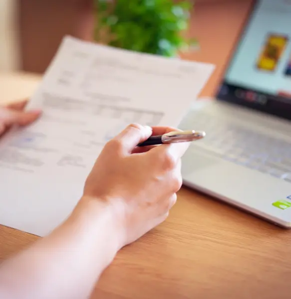 Henkilö tarkistaa rekisteröintiasiakirjaa kynä kädessä
